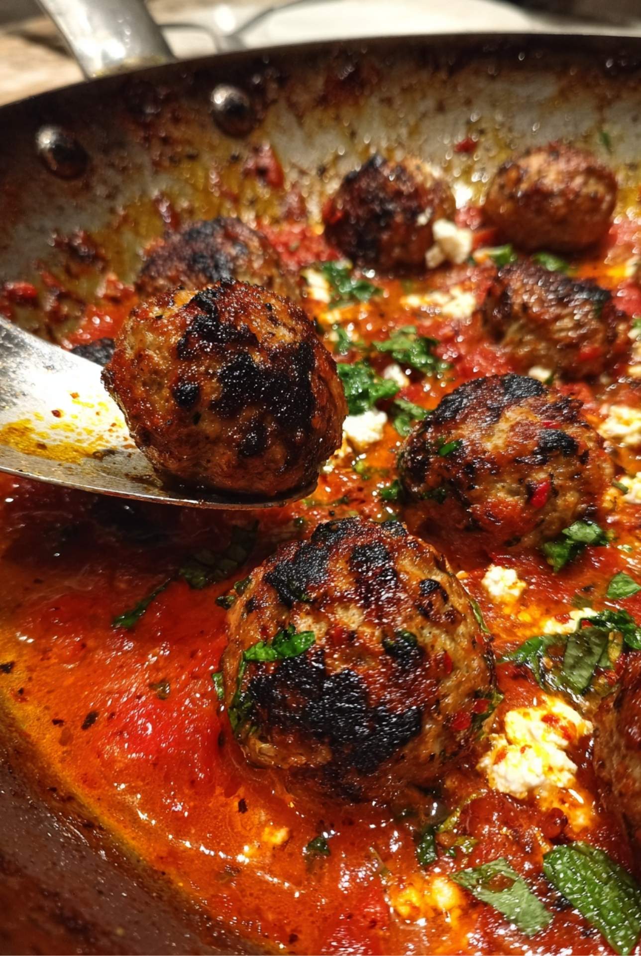 Plated lamb meatballs with spiced tomato sauce, feta crumbles, and fresh mint garnish ready to serve