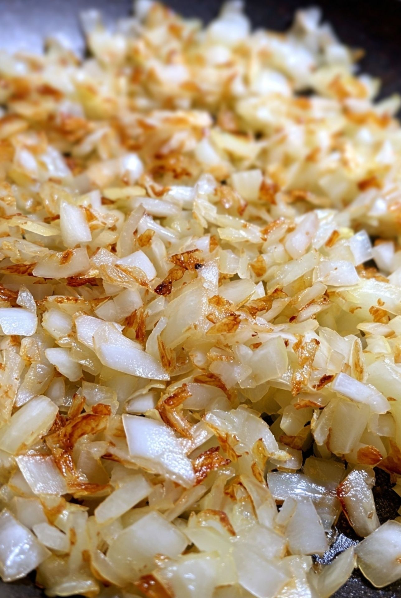 Sautéed chopped onions in a pan – essential flavor base for mama meatloaf recipe.