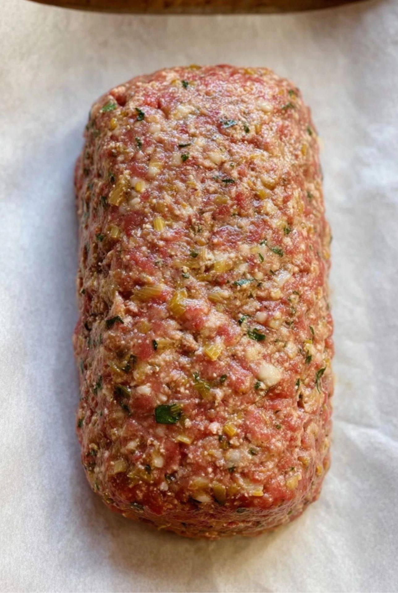 Raw meatloaf mixture shaped into a loaf on parchment paper – mama meatloaf recipe prep step.