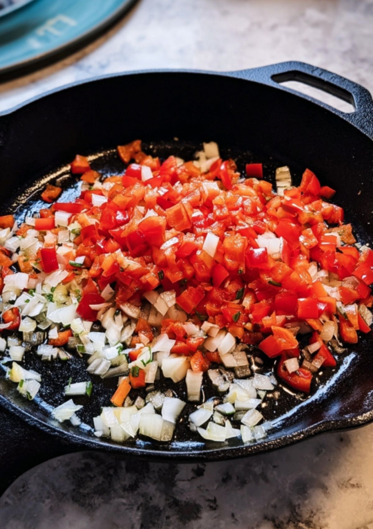 Chopped onions and red bell peppers cooking in a black cast-iron skillet for the base of the turkey taco mixture.