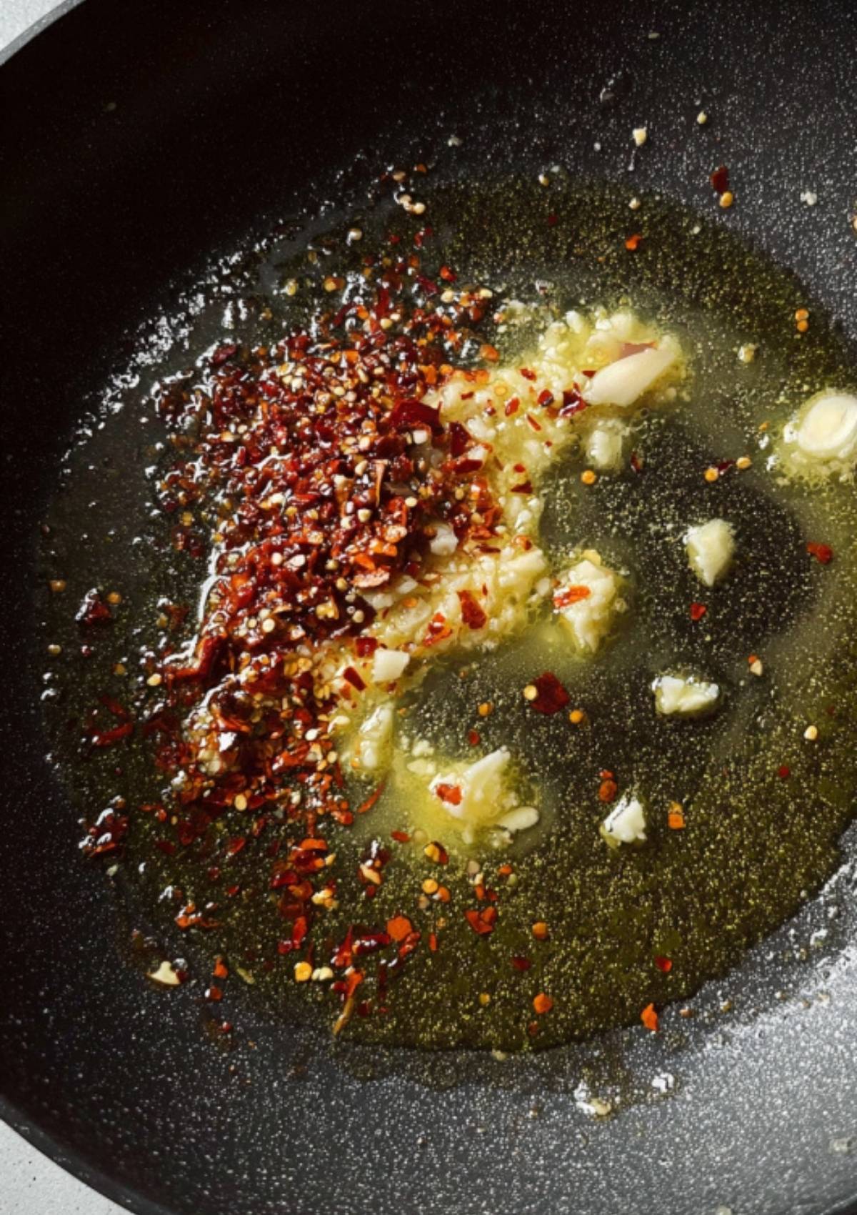 Cubes of butter melting in a hot skillet with minced garlic to create the flavorful garlic butter sauce.