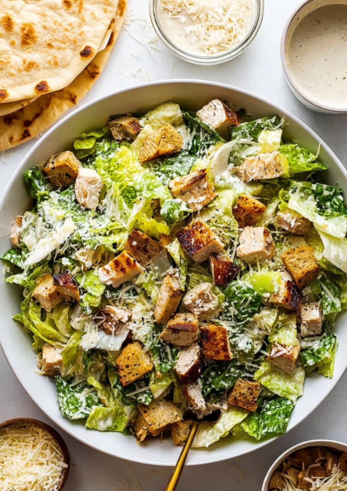 Bowl of chopped romaine lettuce, grilled chicken, croutons, and shredded Parmesan tossed with creamy Caesar dressing.