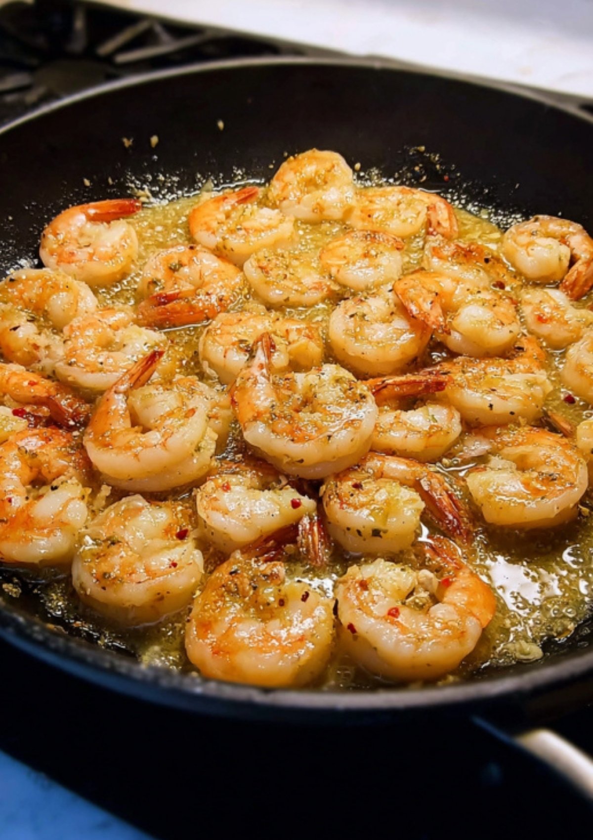 Large shrimp simmering in garlic butter and wine sauce, perfectly cooked and ready to enjoy straight from the pan.