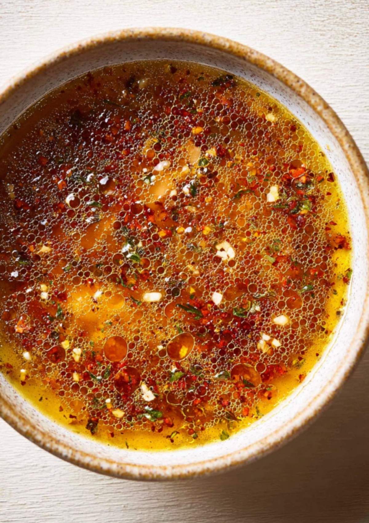 Salmon fillet topped with lemon slices, minced garlic, and sauce on a foil-lined baking sheet ready to cook.