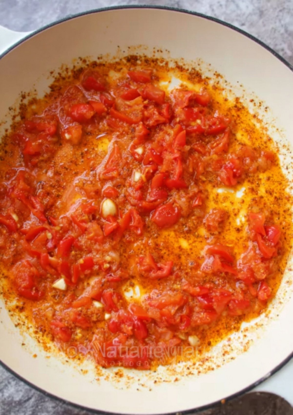 Diced tomatoes and garlic cooking in butter and Cajun seasoning to build flavor for creamy Alfredo sauce.