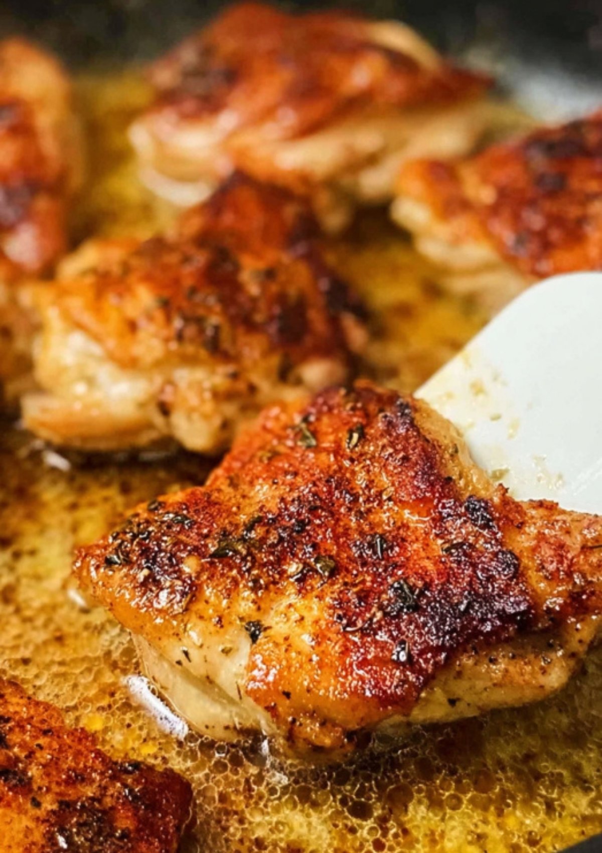 Golden brown chicken thighs searing in a skillet, developing a crispy, flavorful crust for teriyaki chicken rice bowls.