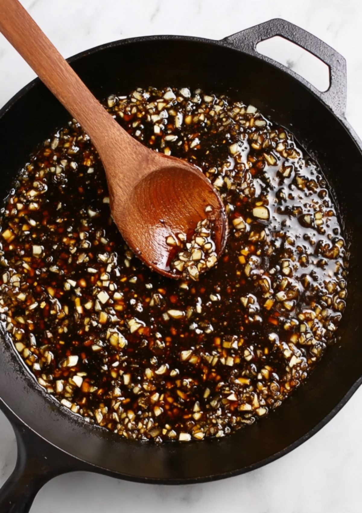 Cooked chicken thighs plated on a dish with sticky sauce and a sprinkle of fresh herbs.
