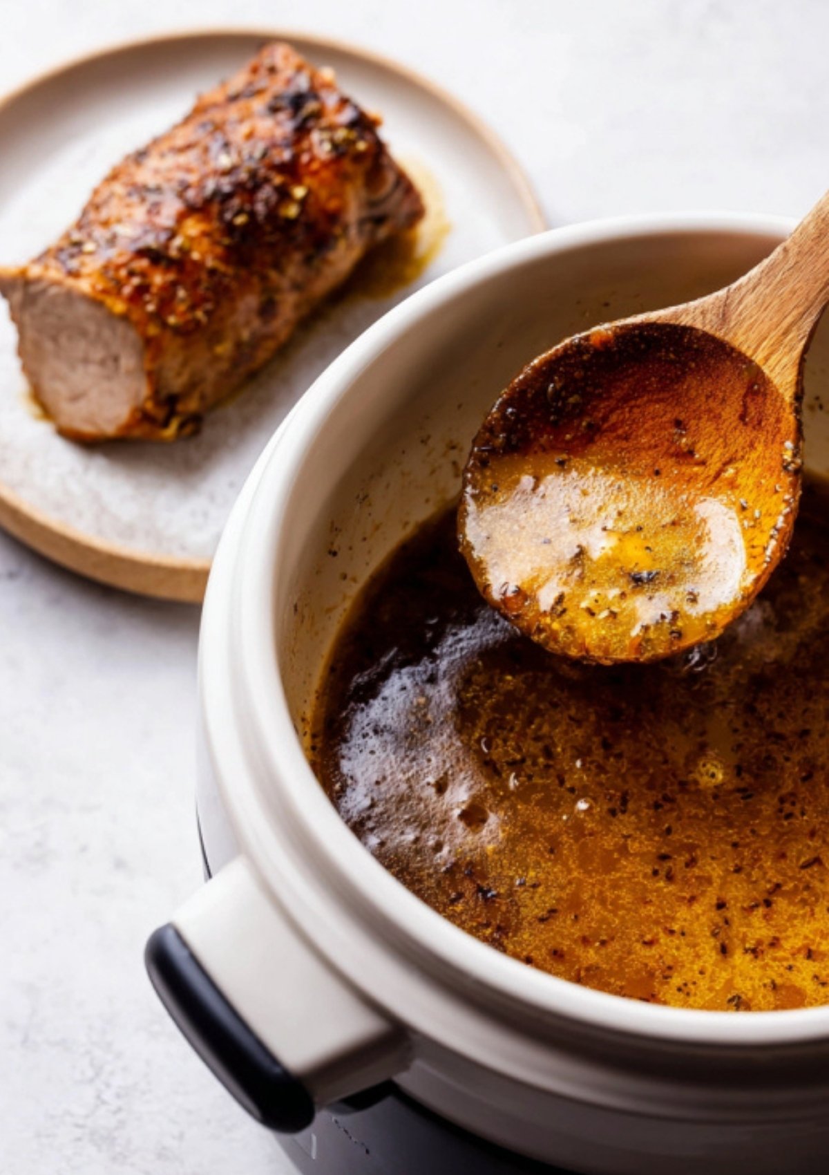 Juicy slices of pork tenderloin arranged on a plate, drizzled with thick maple Dijon gravy and garnished with thyme.