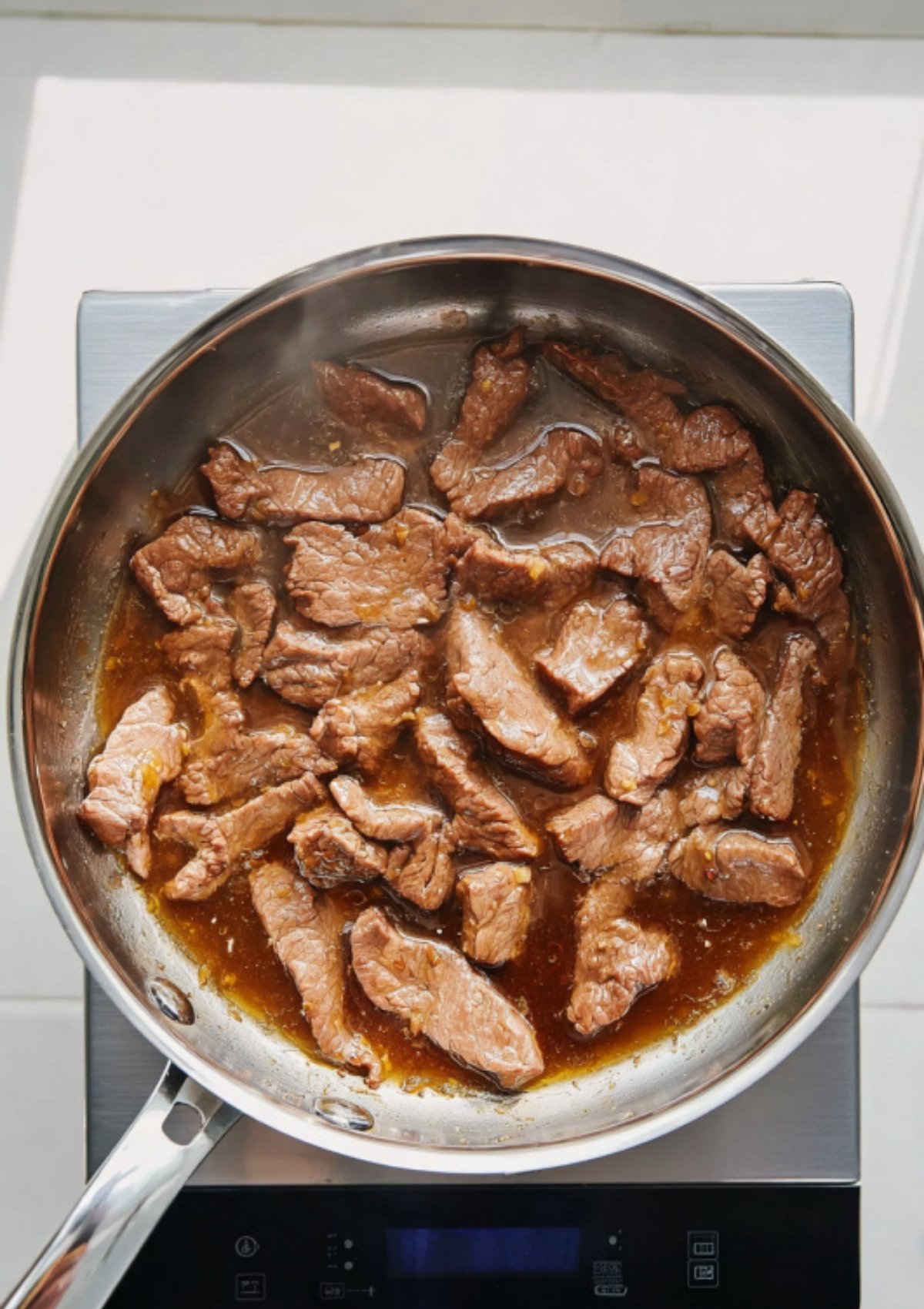 Bowl of beef and broccoli stir-fry served over fluffy white rice with chopsticks on the side.