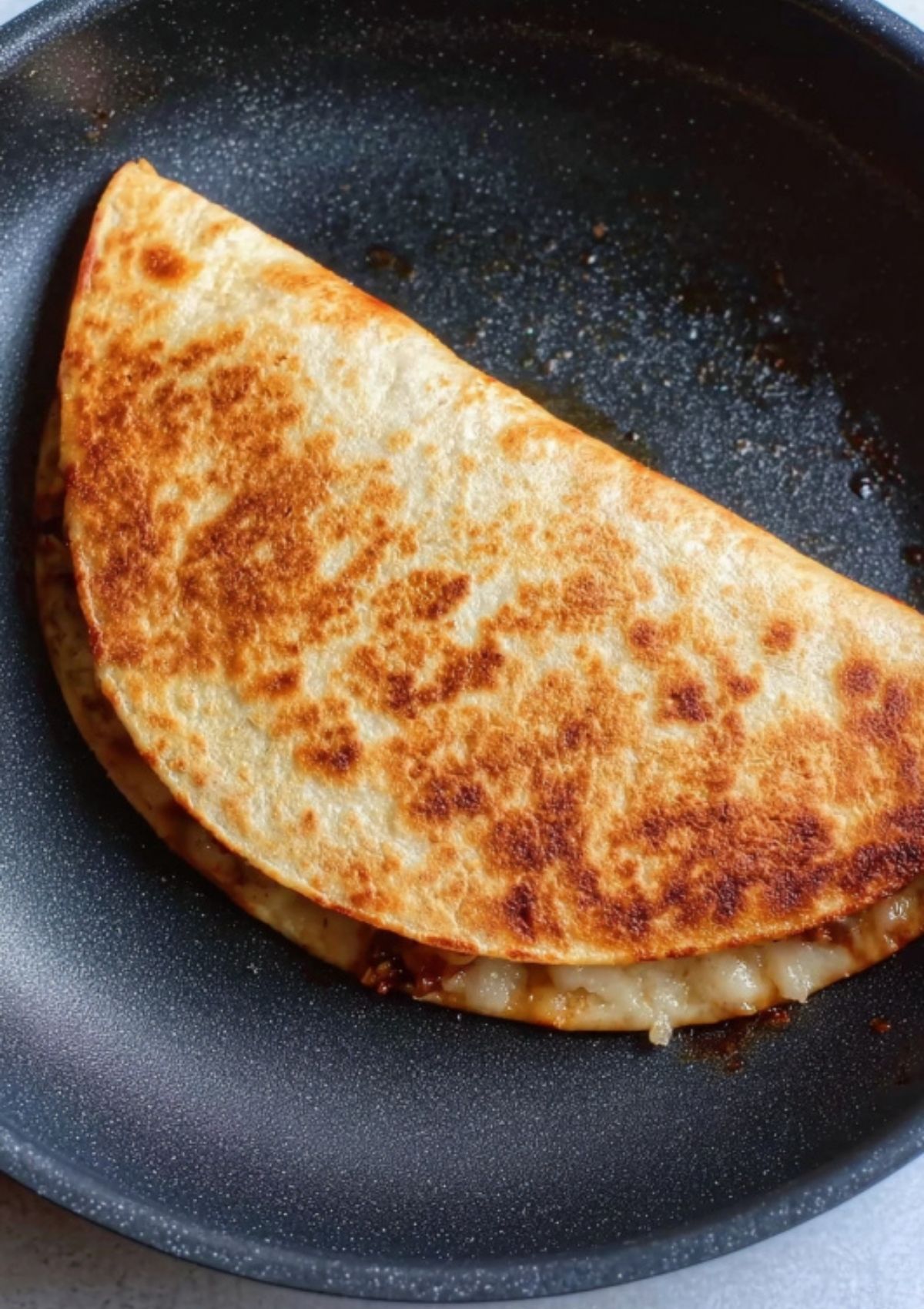 Warm BBQ chicken quesadillas cut into wedges on a wooden board beside a bowl of salsa.