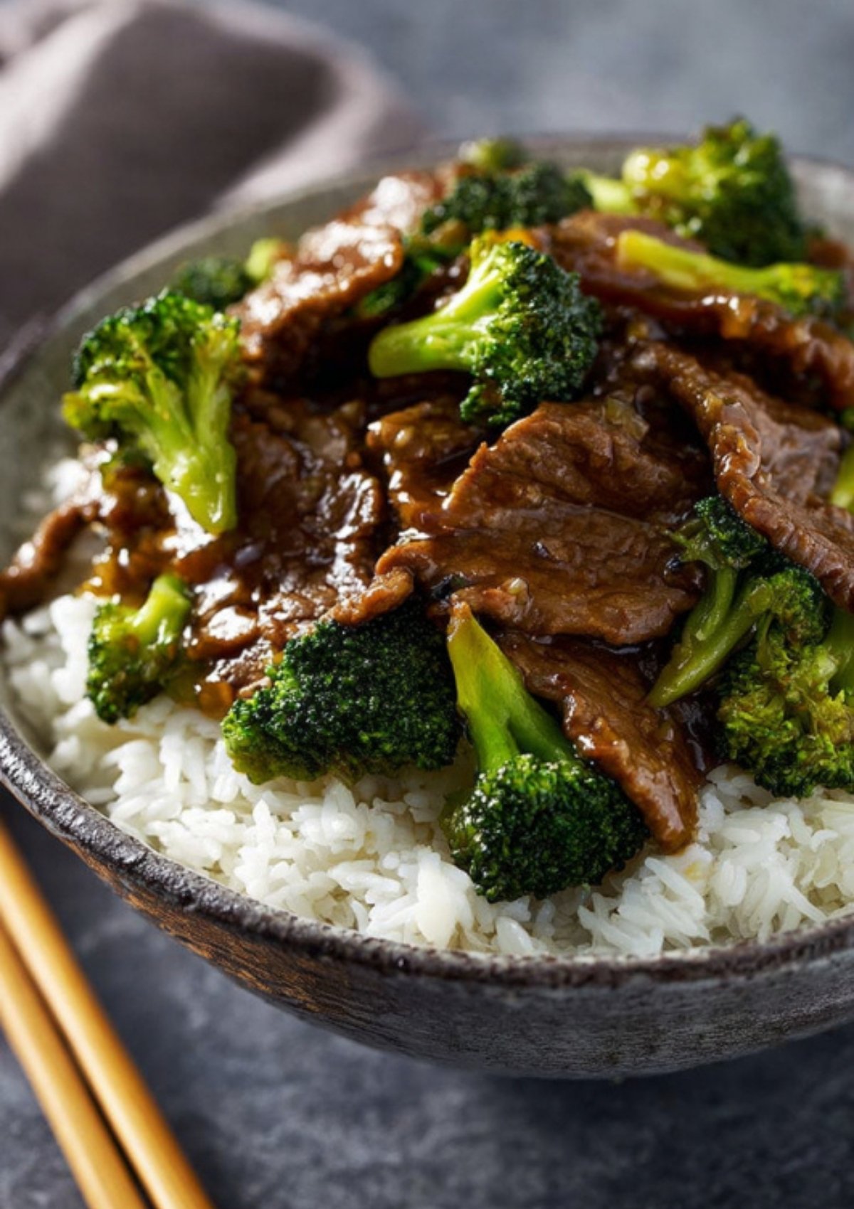 Strips of beef simmering in rich brown stir-fry sauce in a stainless-steel skillet on the stove.