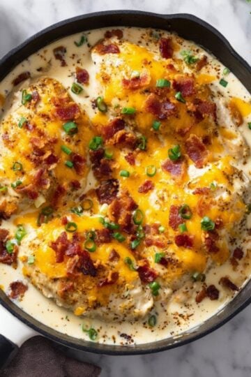 Skillet filled with bacon ranch chicken bake topped with melted cheddar, crispy bacon, and green onions, ideal for creamy chicken dinners and easy comfort food.