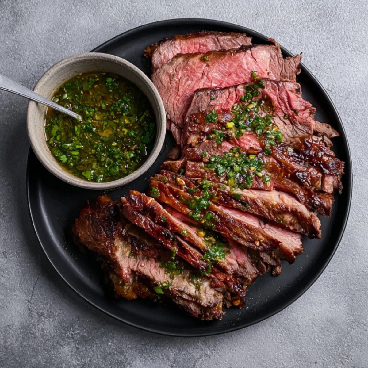 Plate of tender grilled chuck roast slices served with a bowl of homemade chimichurri—ideal for holiday roast or family gatherings.