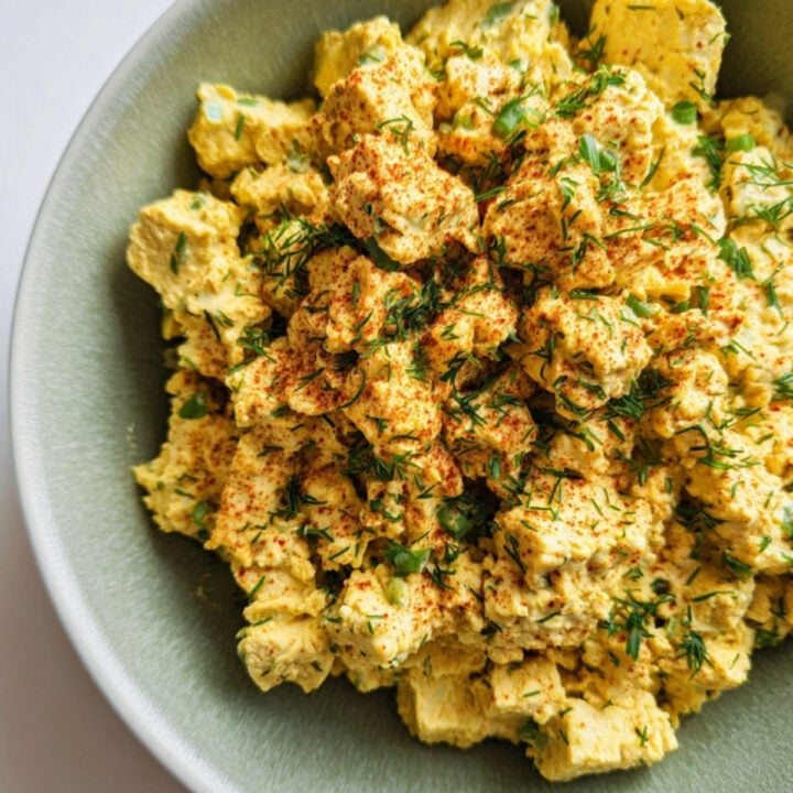 Bowl filled with a plant-based tofu egg salad, seasoned with herbs and spices for a satisfying, protein-packed vegan meal.