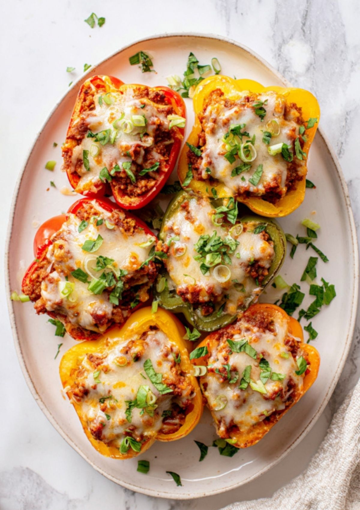 Colorful Sloppy Joe Stuffed Peppers served on a plate and topped with fresh parsley and green onions