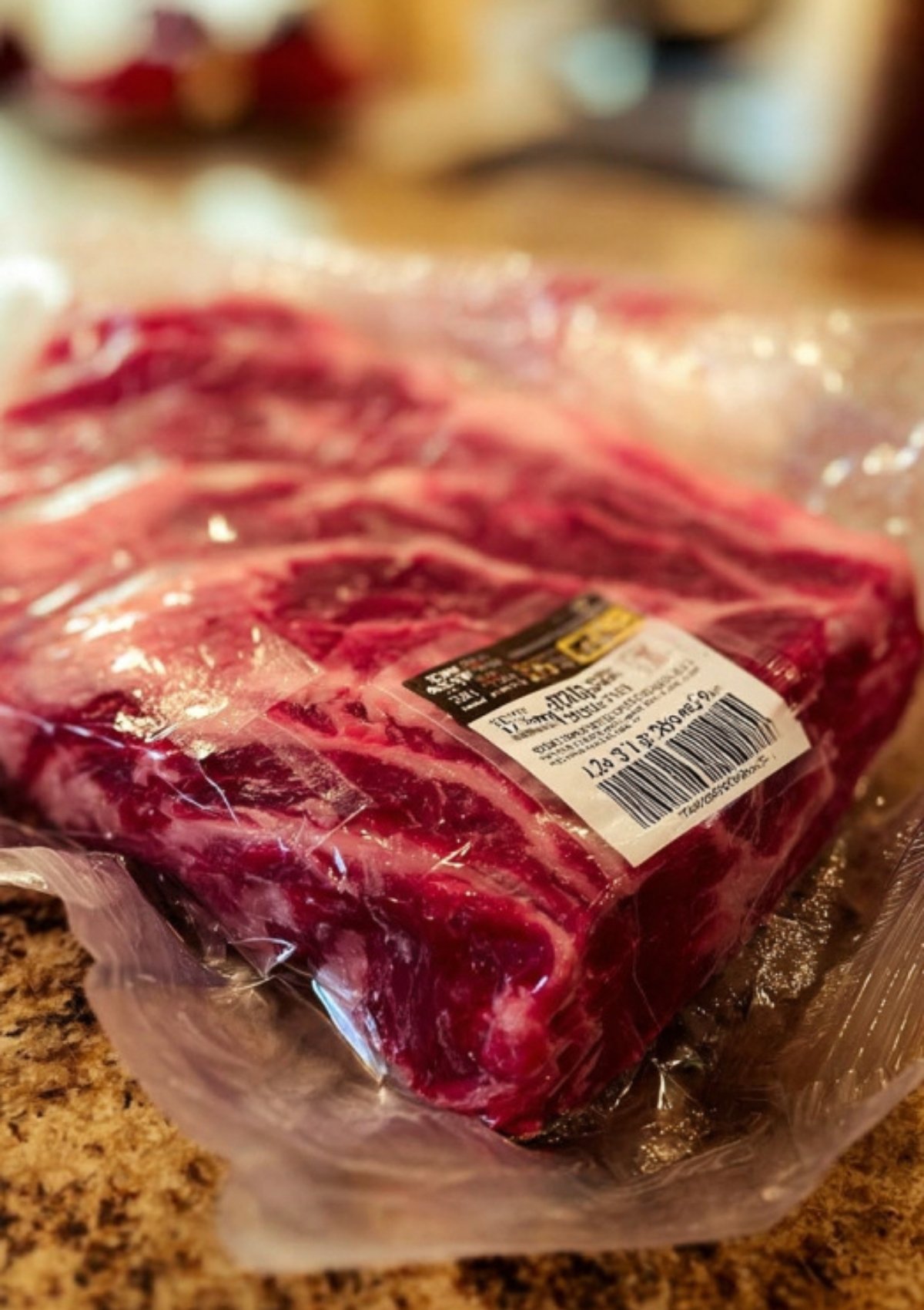 Raw ribeye roast in packaging on a kitchen counter, marbled and ready to cook