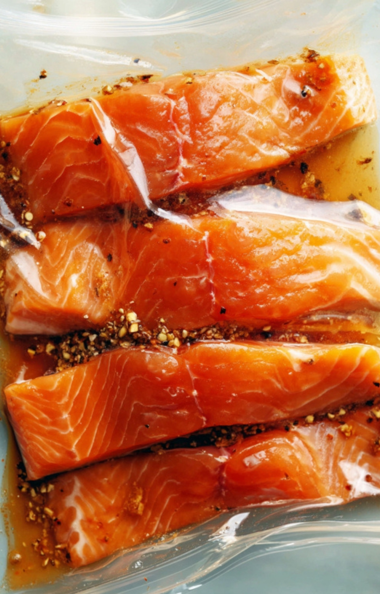 Salmon fillets soaking in a maple-soy marinade inside a plastic bag, ready for baking.