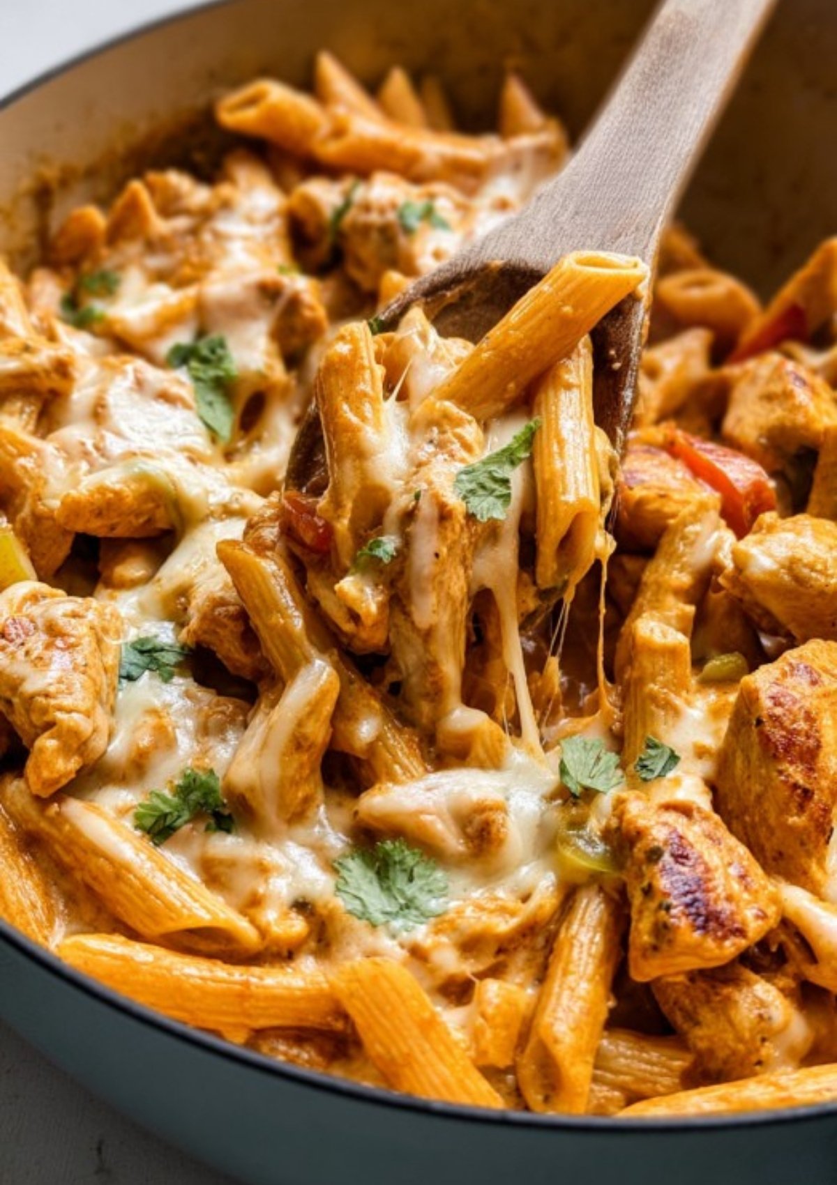 Creamy chicken fajita pasta topped with melted cheese and fresh cilantro, served hot in a skillet for a cozy family dinner.