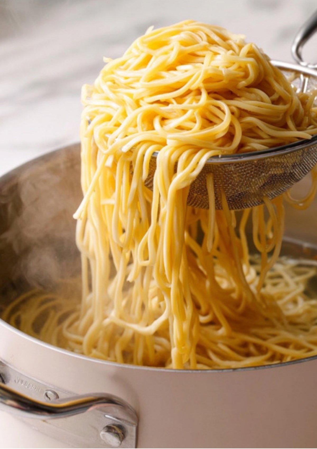 Chopsticks lifting glossy soy sauce noodles with scallions, showing the savory glaze and perfect chewy texture.