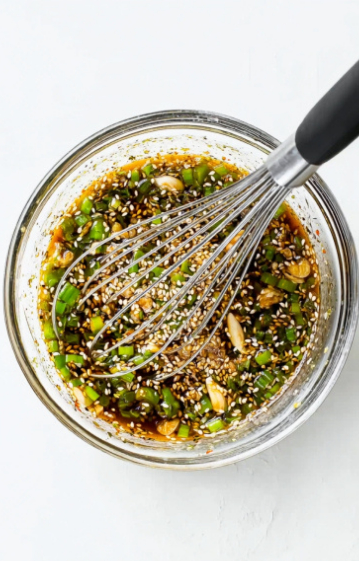 Soy sauce marinade being whisked with scallions, garlic, and sesame seeds in a bowl