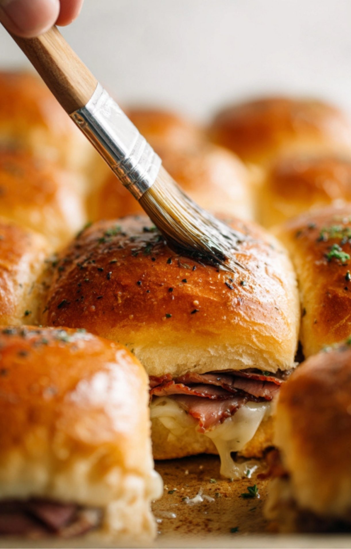 Soft dinner rolls filled with roast beef and melted cheese, topped with garlic butter and fresh herbs for the best baked sliders.