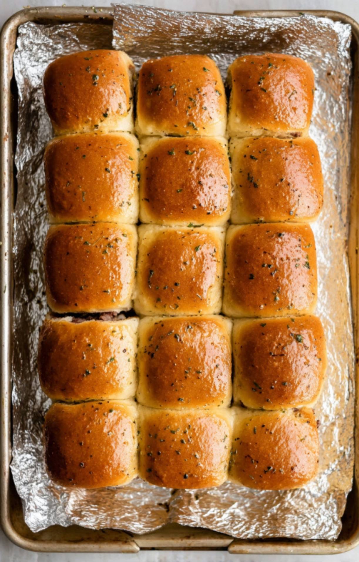 A full tray of golden baked roast beef sliders, soft and buttery, fresh from the oven and ready to serve.