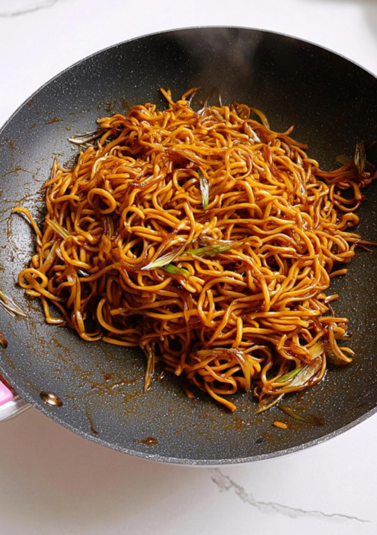 Fresh noodles tossed in a savory soy sauce mix, caramelizing in a hot wok for quick Cantonese-style stir fry.