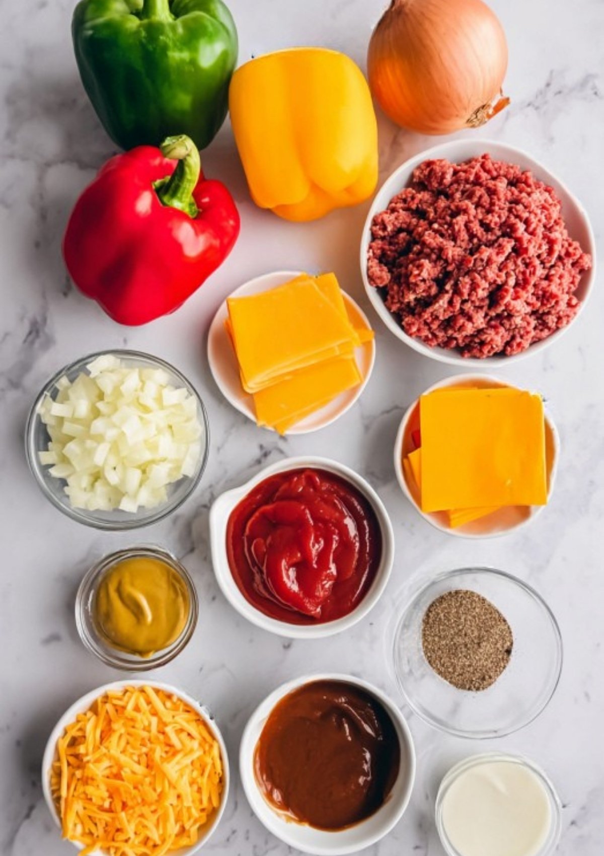 Bowls of ground beef, chopped peppers, onions, cheese, ketchup, mustard, and seasonings for stuffed pepper recipe