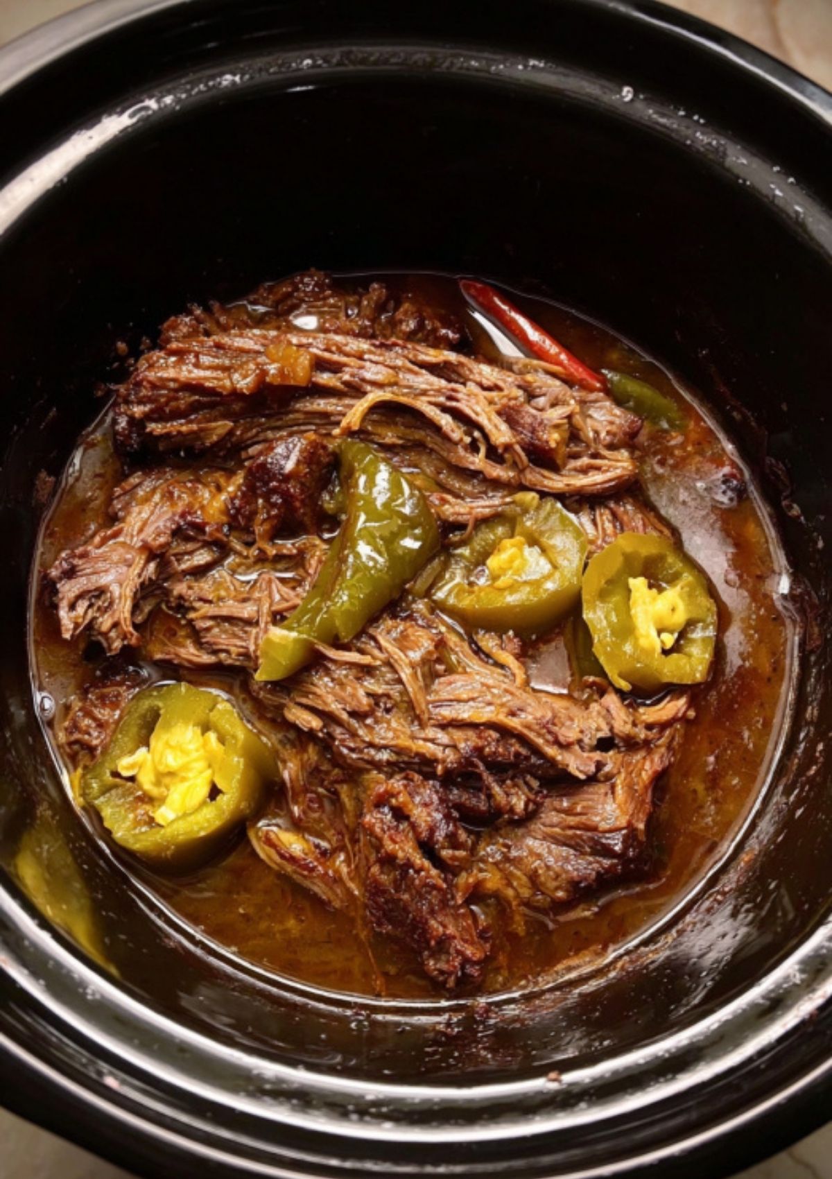 Slow cooker filled with tender Mississippi pot roast simmering in its own juices, loaded with tangy pepperoncini peppers.