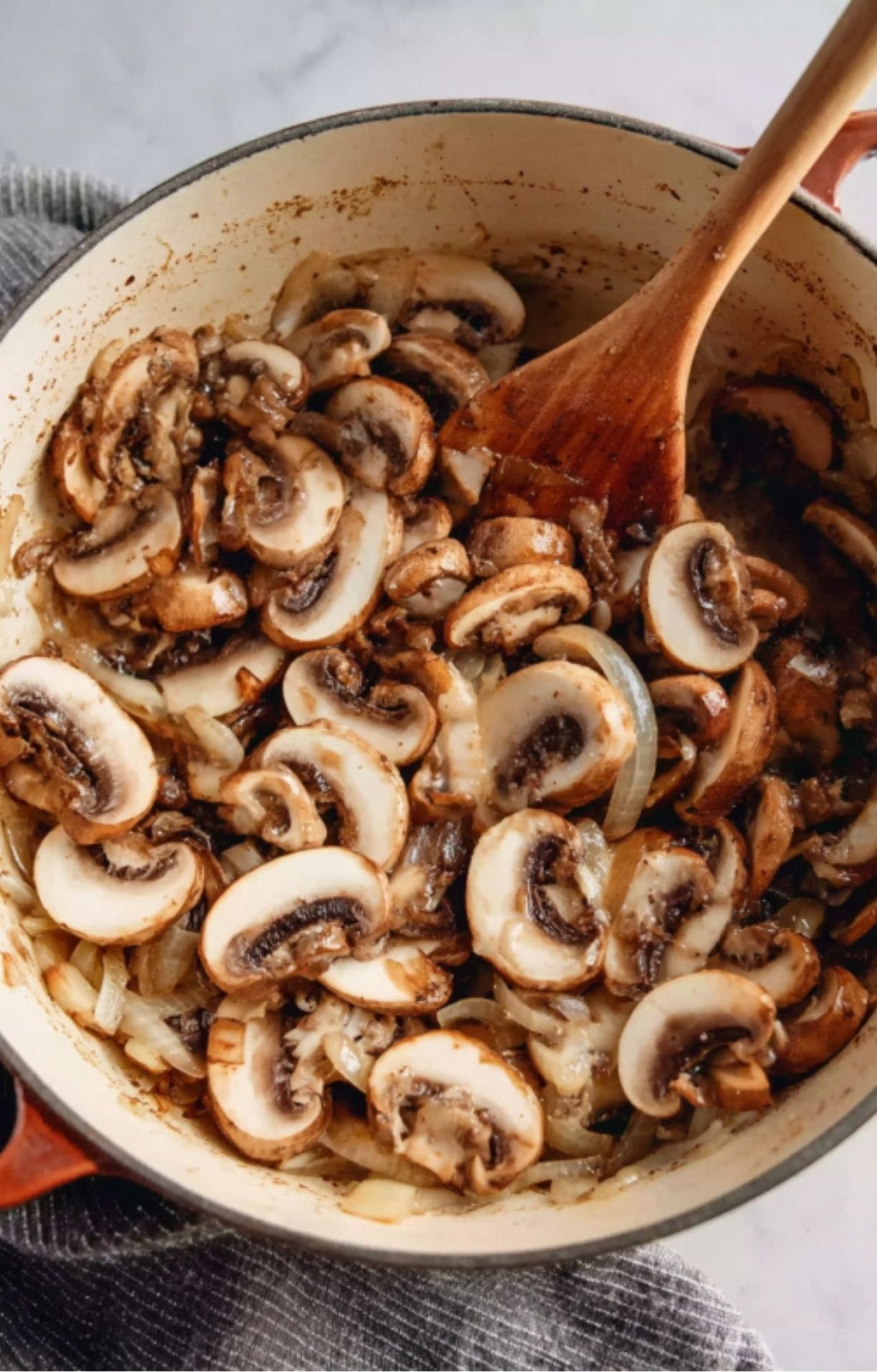 Golden mushrooms and onions being sautéed in a Dutch oven as the flavorful base for homemade leftover roast beef stroganoff.
