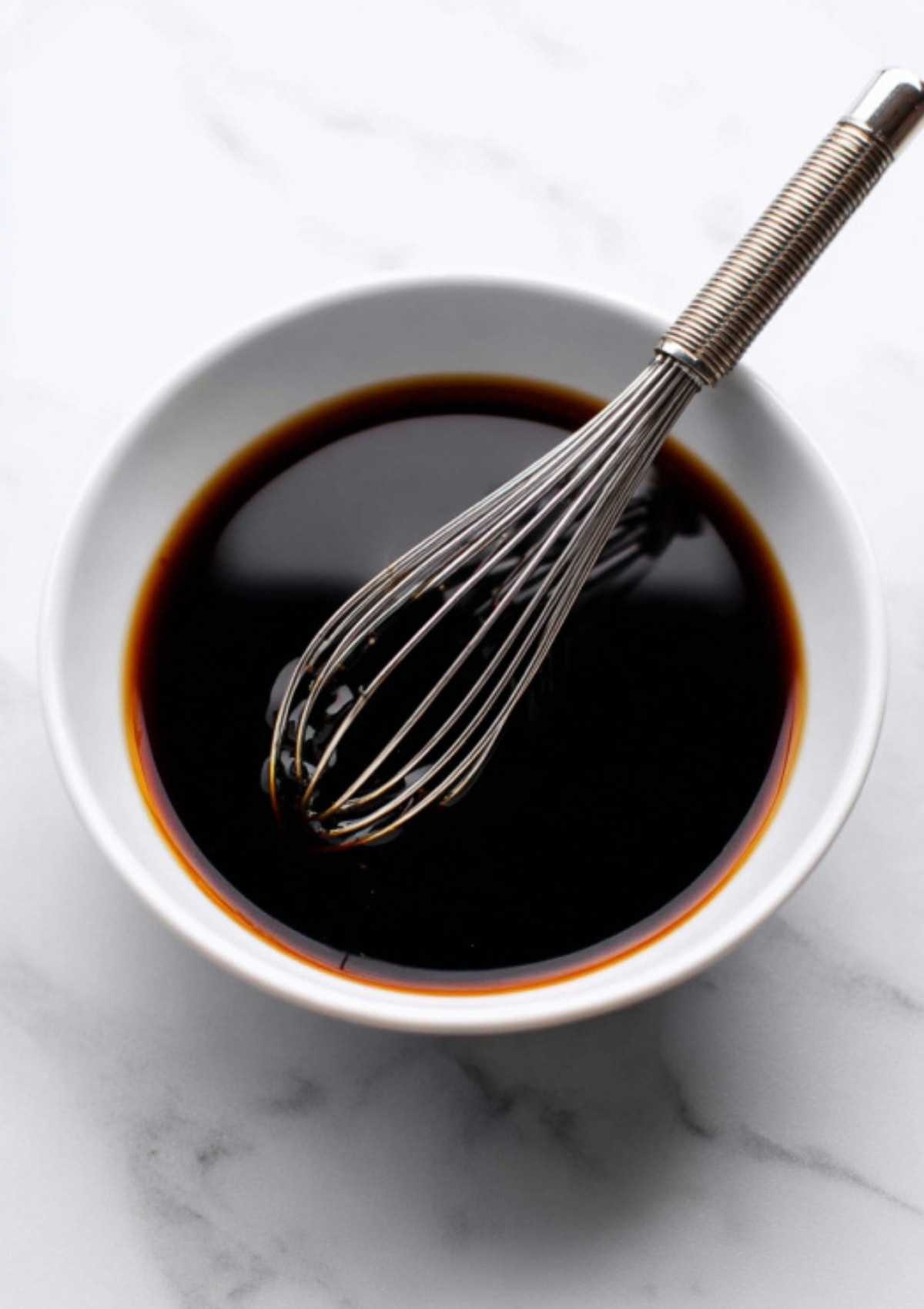 Bowl of dark soy-based sesame sauce being whisked together.