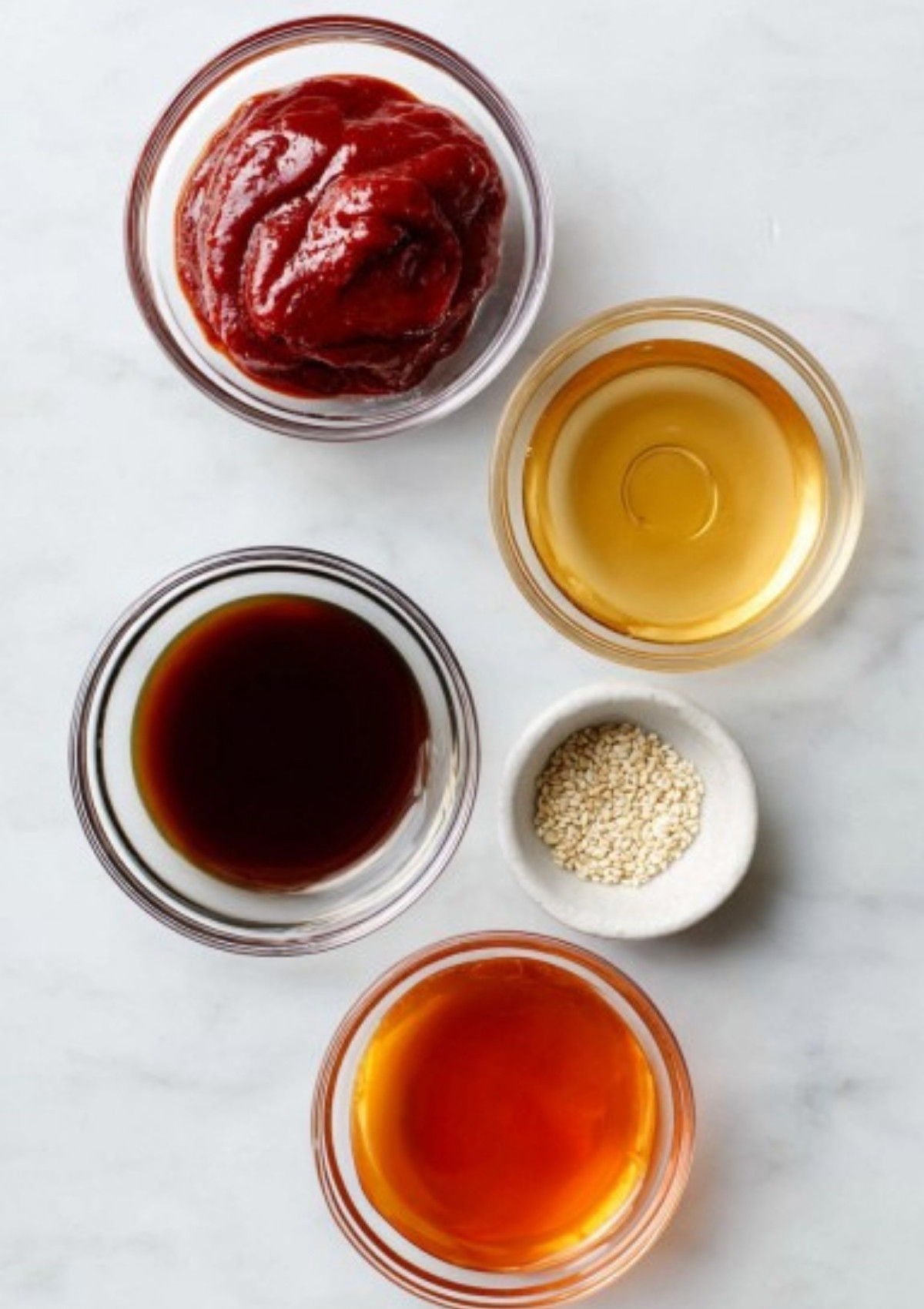 Small bowls with gochujang paste, sesame oil, rice vinegar, soy sauce, and sesame seeds
