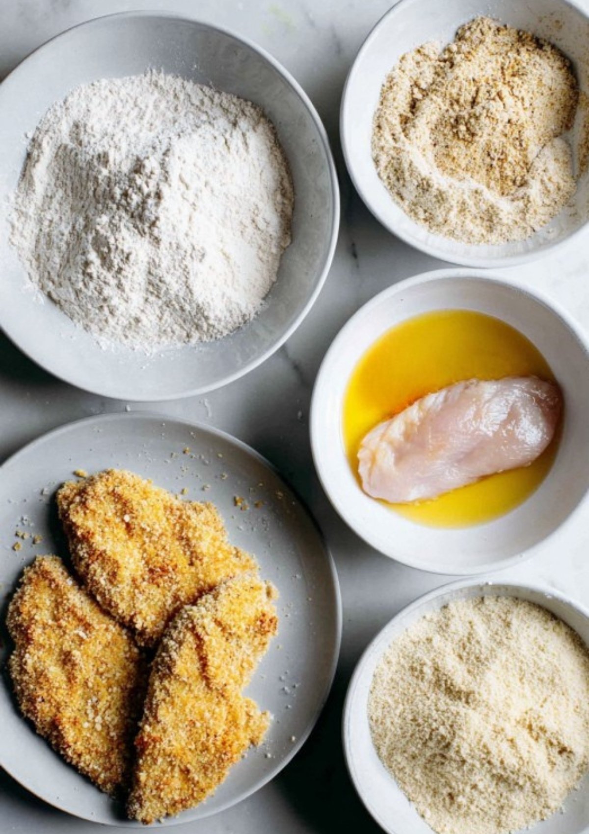 Step-by-step bowls with flour, egg, and breadcrumbs showing how to bread chicken for homemade chicken parmesan sandwiches.