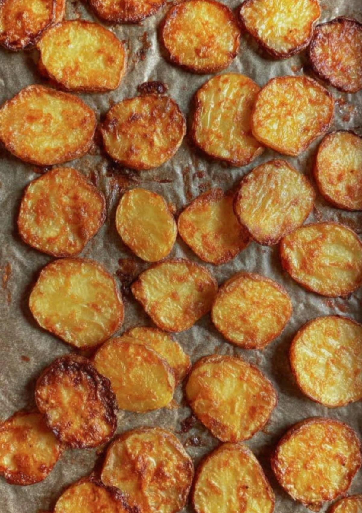 Baking tray with golden, crispy roasted potato slices, evenly spaced and ready for nacho toppings.
