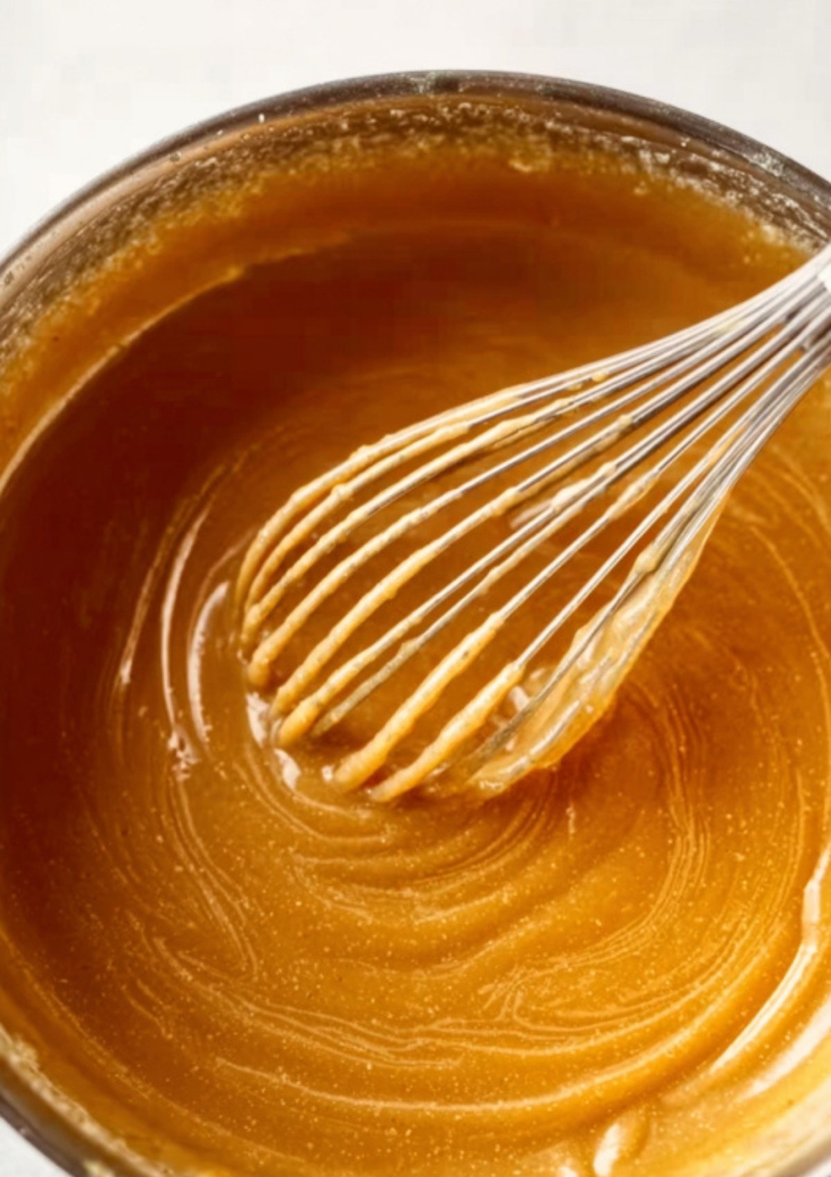 Peanut sauce being whisked in a bowl until creamy and glossy.