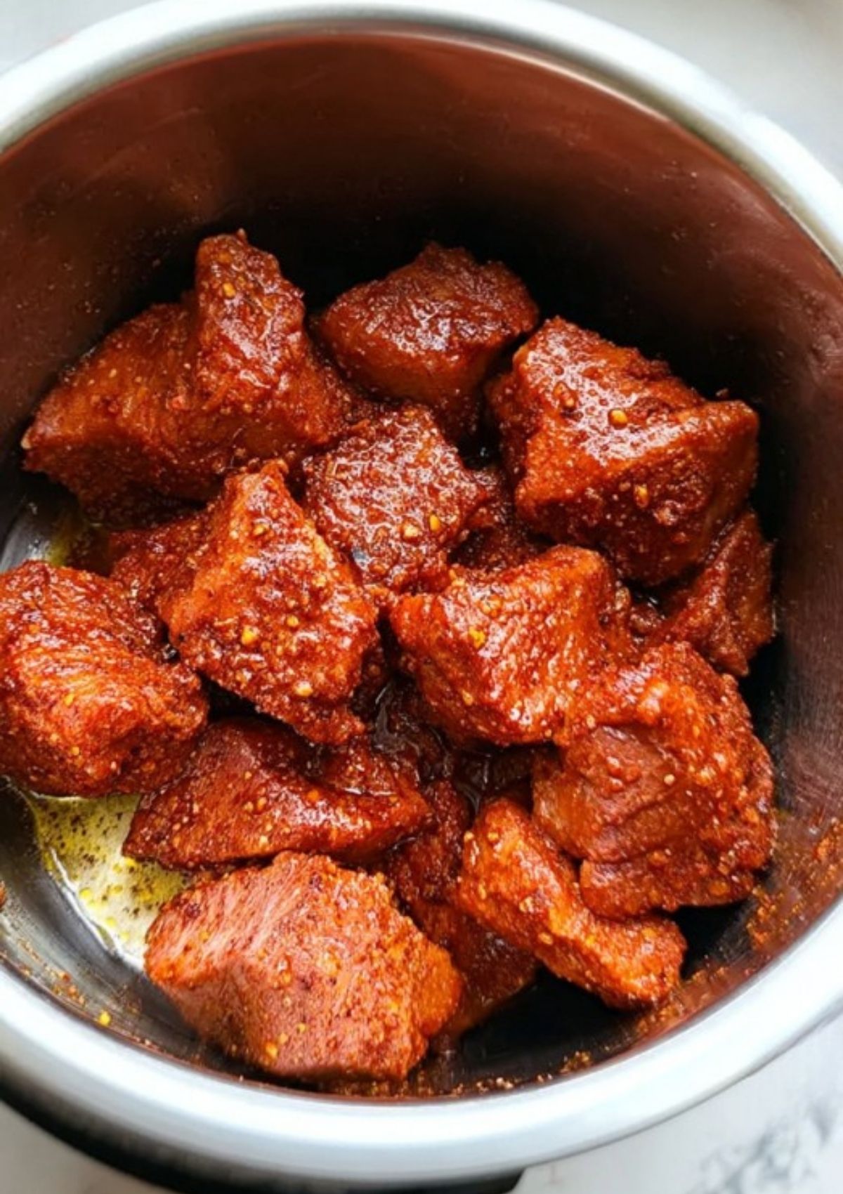 Pork pieces coated in spice rub in an Instant Pot, prepped for pulled pork sandwiches.