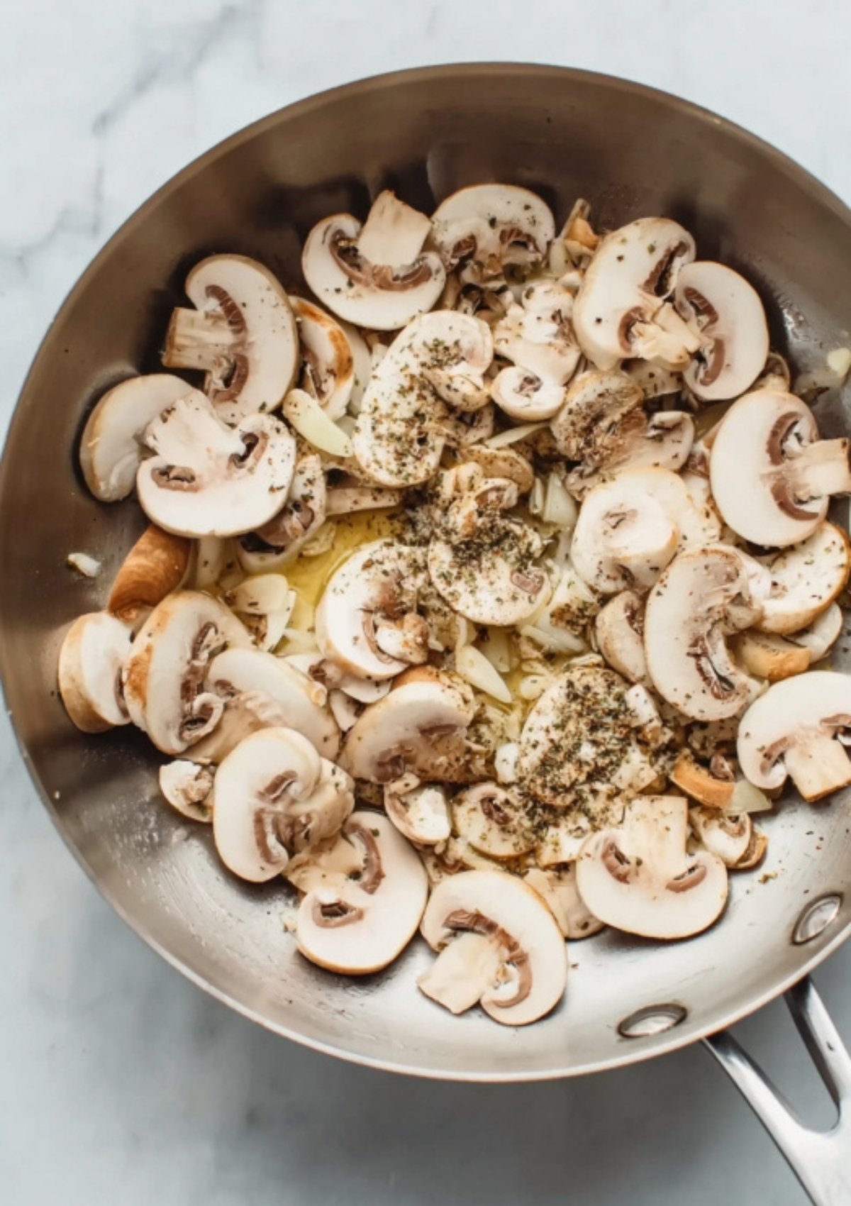 Freshly sliced mushrooms, chopped onions, and Italian seasoning sizzling in olive oil, ready to build flavor for creamy mushroom gnocchi.
