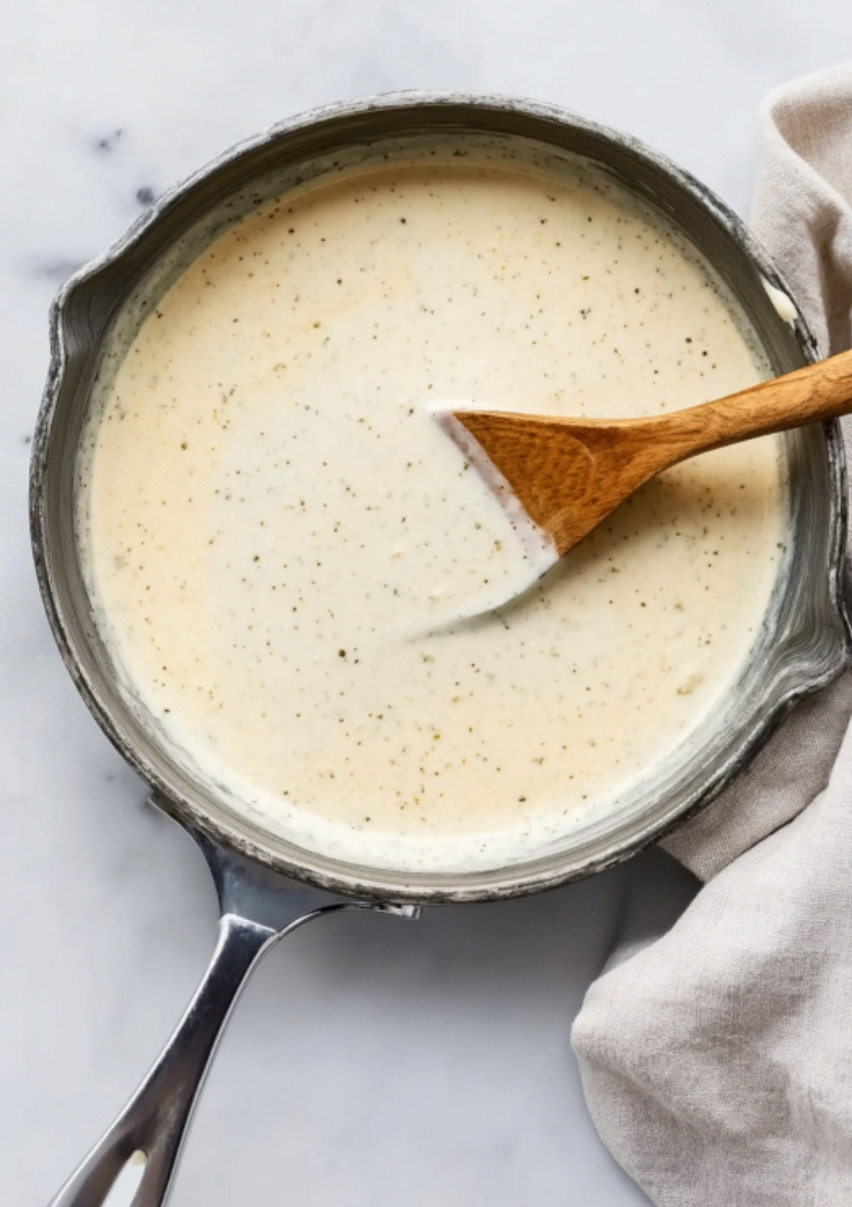 Rich and smooth homemade ranch sauce in a saucepan, ready to use for bacon ranch chicken casserole and keto chicken recipes.