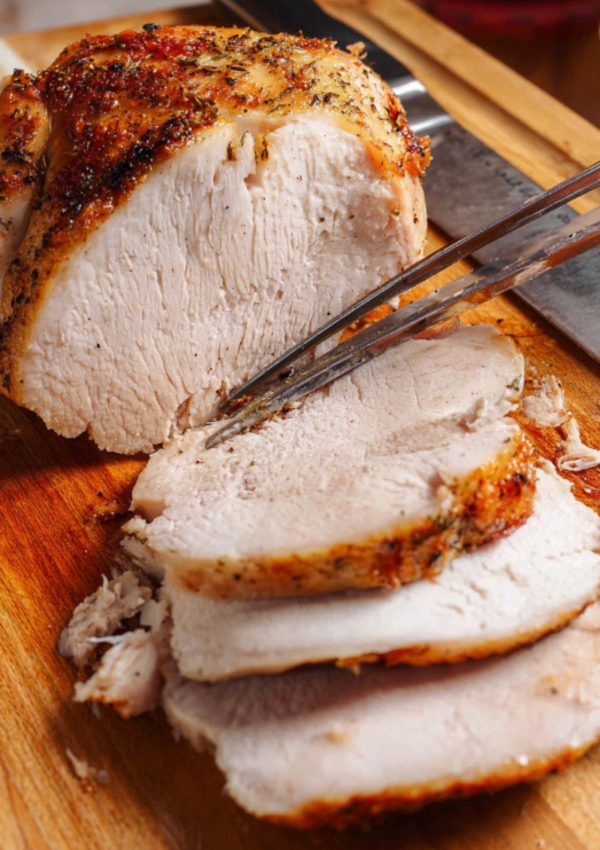 Carving a perfectly roasted Butterball turkey breast on a wooden cutting board.