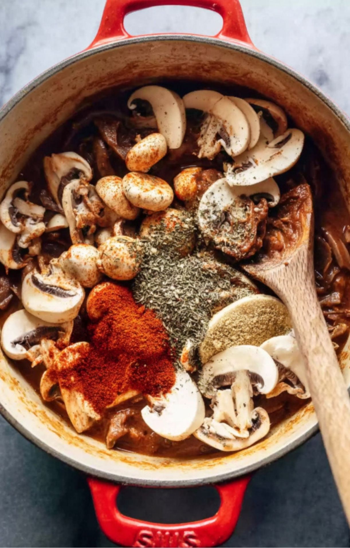 Dutch oven filled with sliced mushrooms, dried herbs, smoked paprika, and seasoning, ready to make an easy leftover roast beef stroganoff.