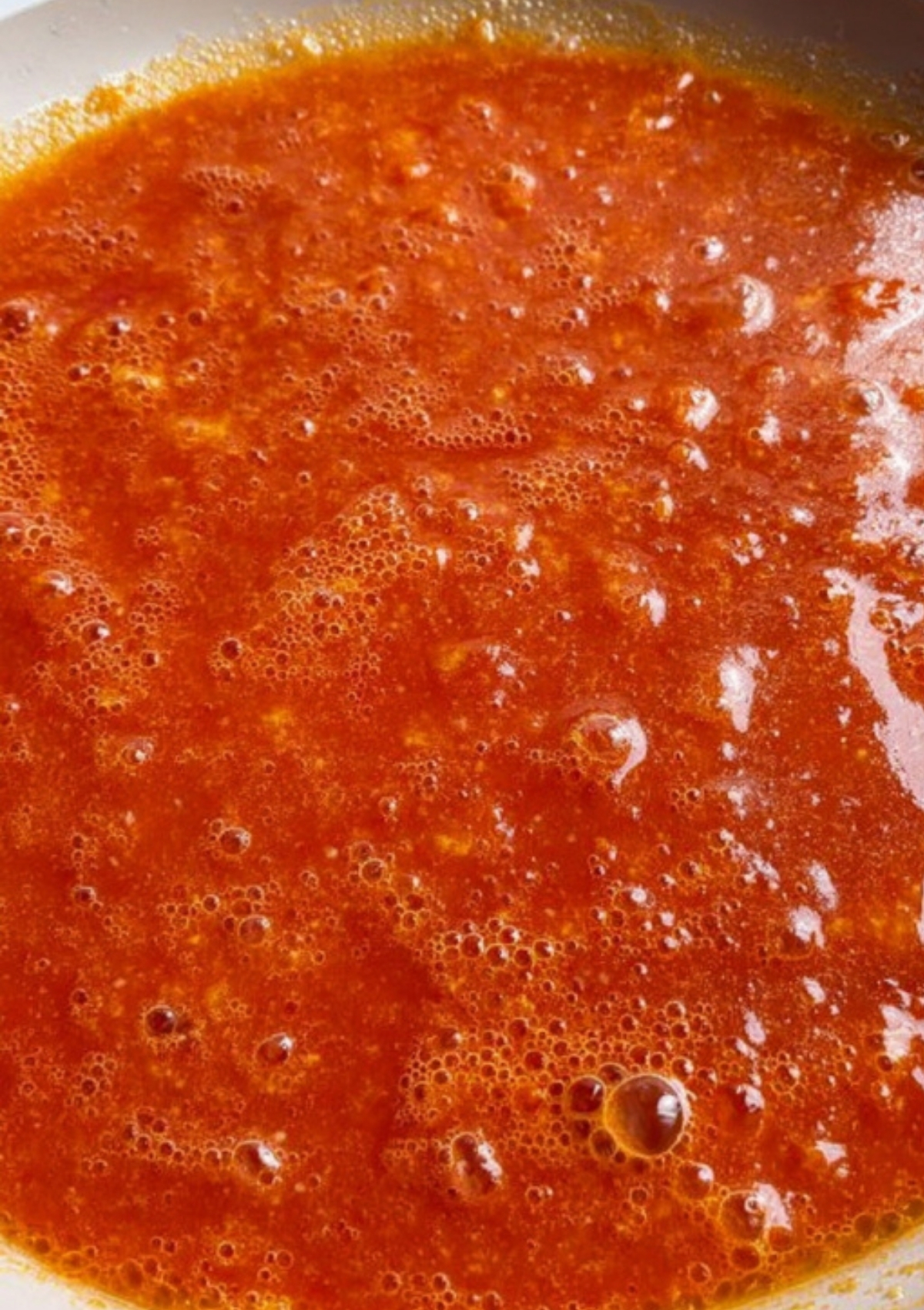 Beaten eggs and tomato mixture simmering in a frying pan, ready for making egg sauce.