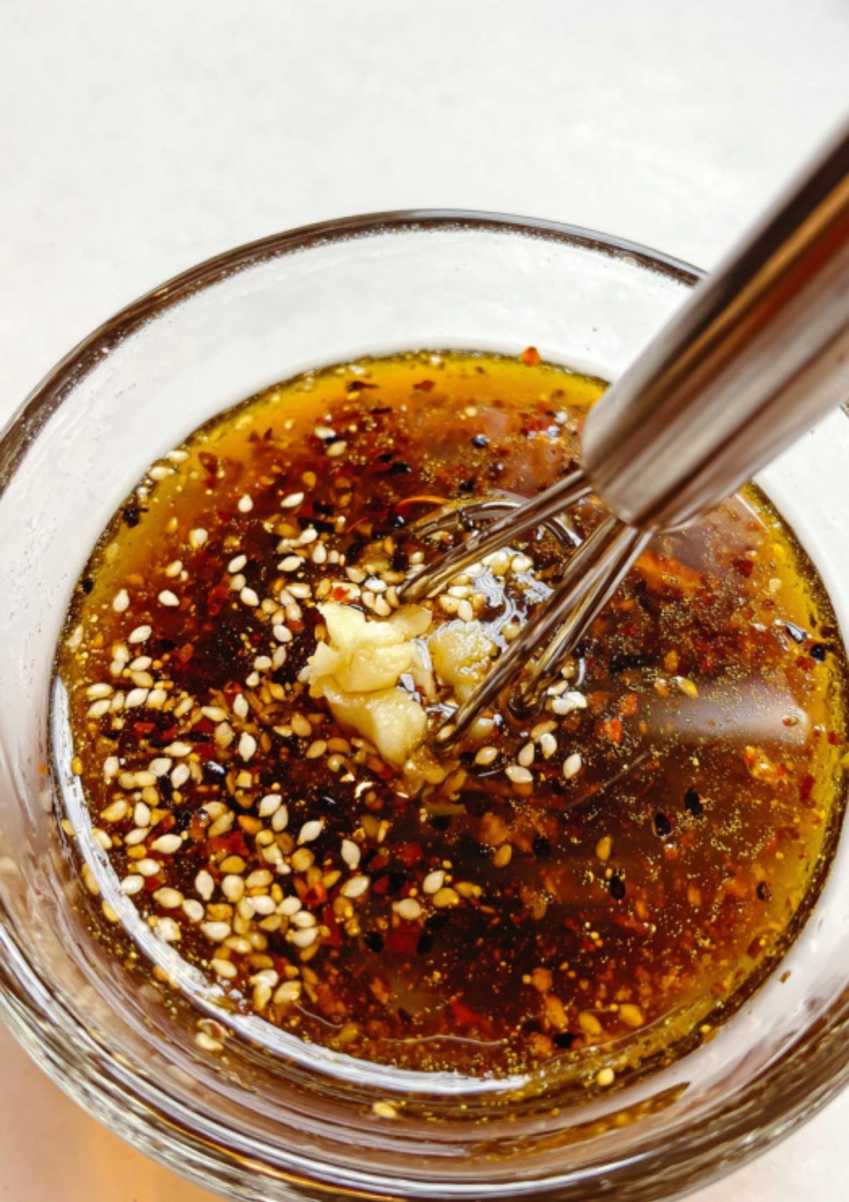 Soy ginger sauce with fresh garlic, sesame, and chili flakes being mixed in a glass bowl. Perfect for meal prep, Asian bowls, and grilling.