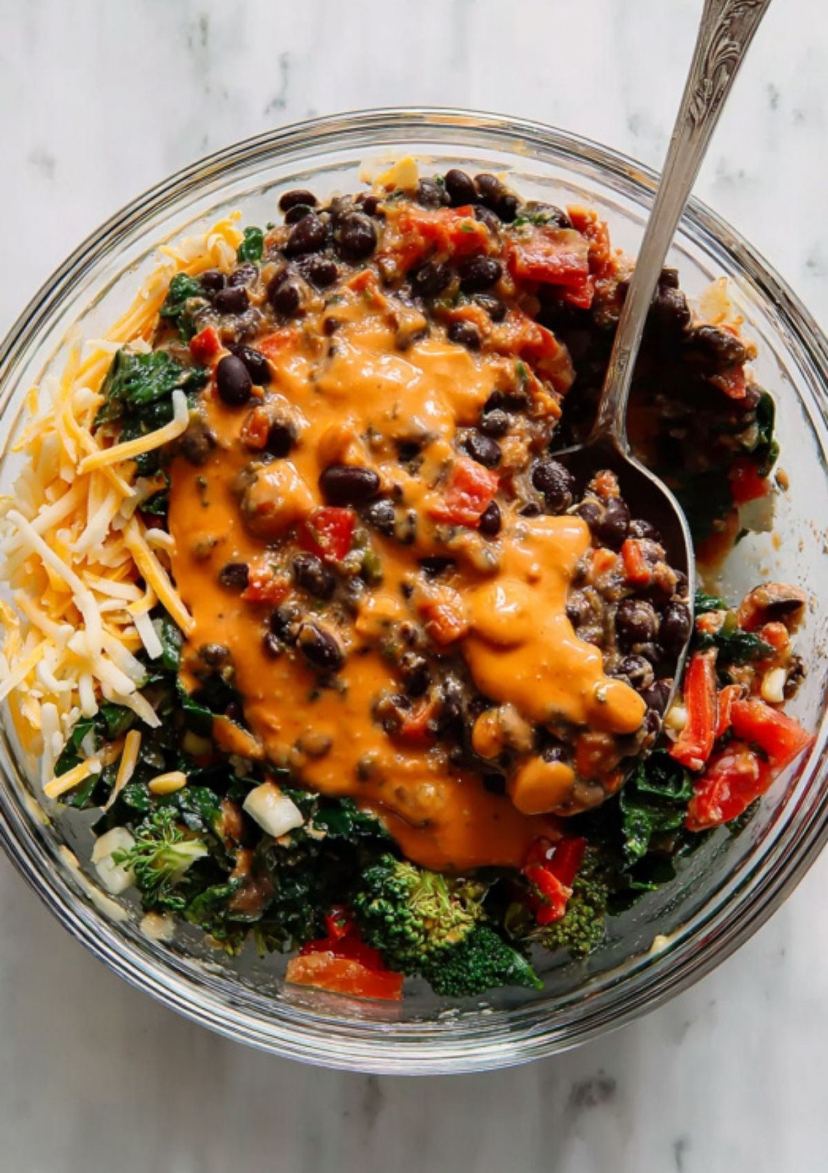 Mixing bowl of black beans, broccoli, spinach, cheese, and red peppers for a healthy vegetarian enchilada filling.
