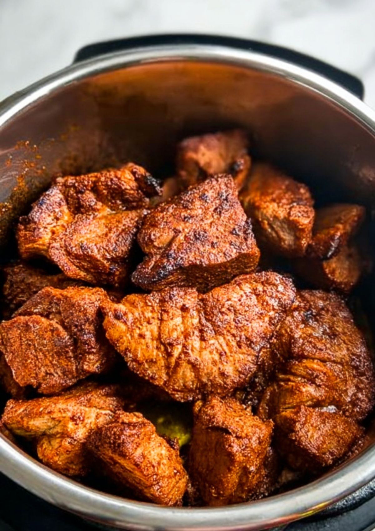 Golden brown pork chunks seared in an Instant Pot before slow cooking for pulled pork.