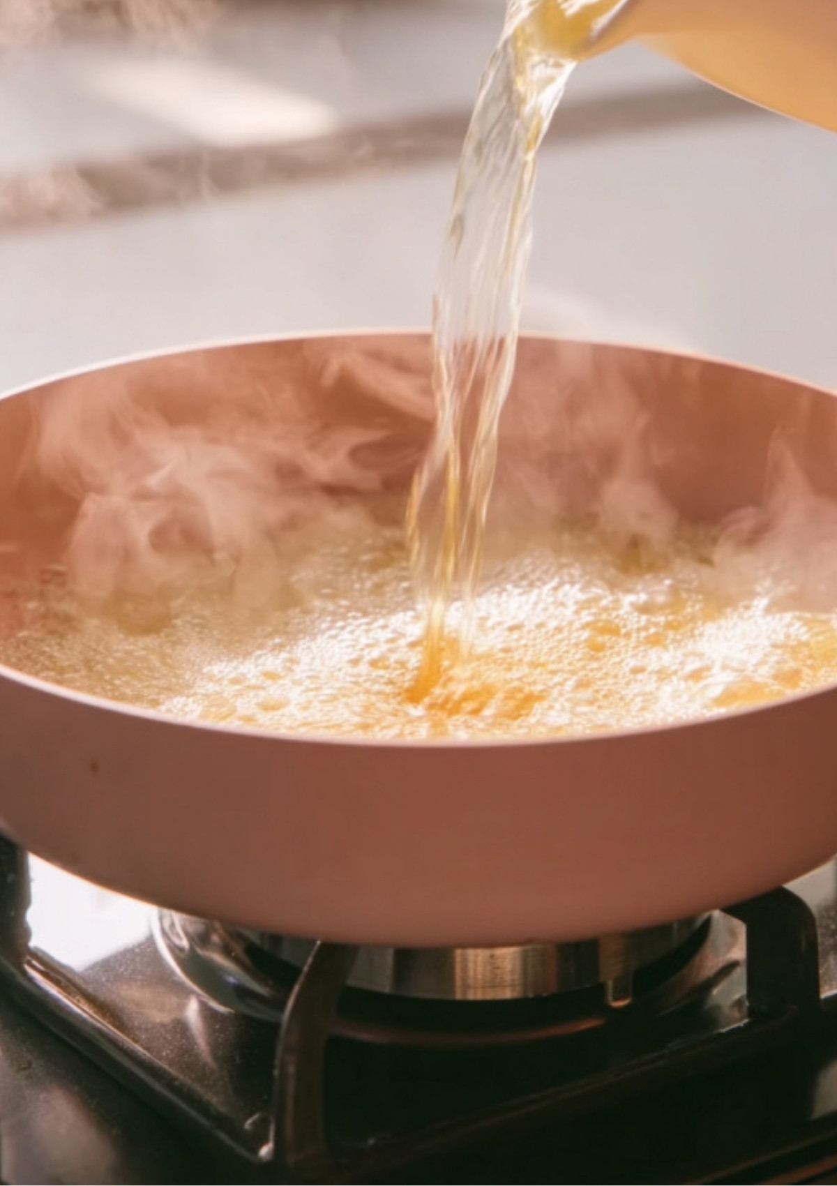 Pouring broth into buttery garlic sauce for garlic butter shrimp pasta