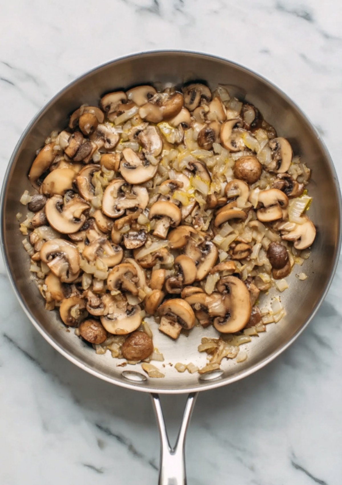 Sautéed mushrooms and onions in a stainless steel skillet, the savory base for creamy mushroom gnocchi. Easy vegetarian recipe starter.
