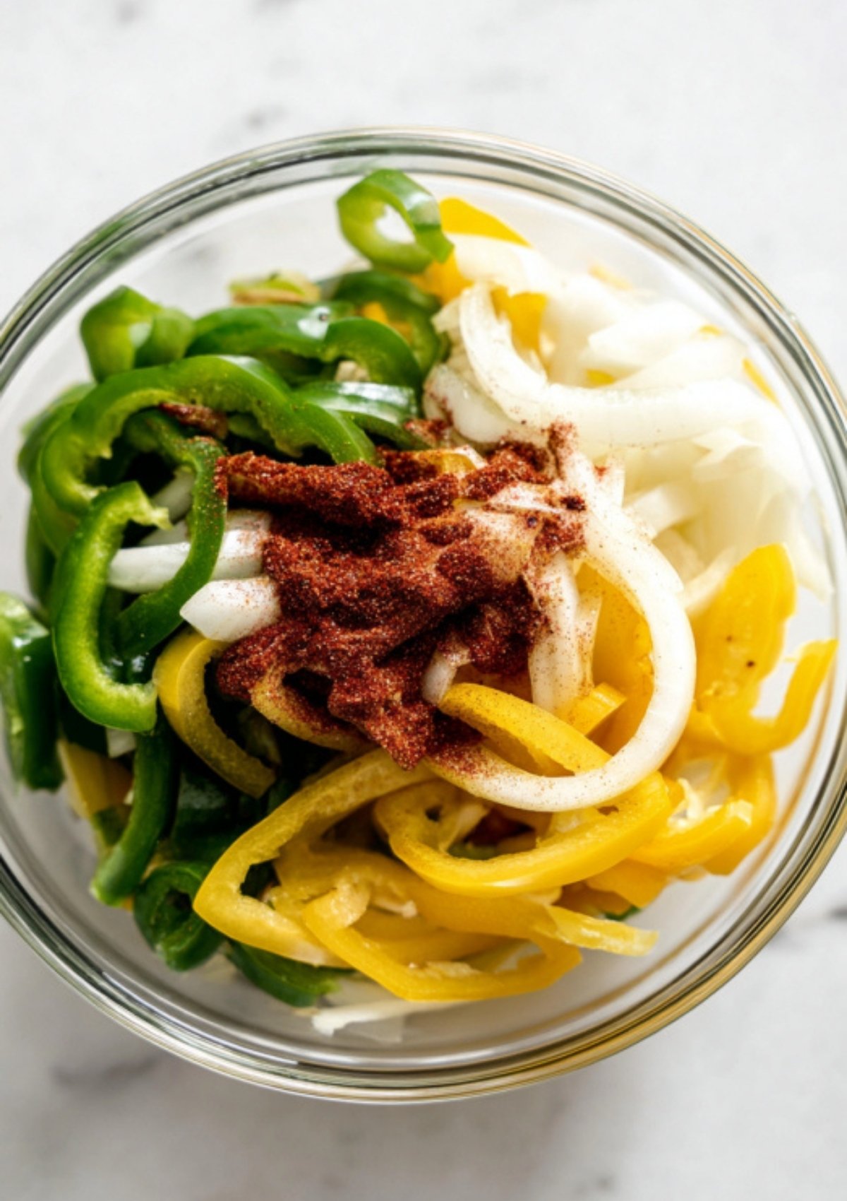 Bowl of green and yellow bell peppers, sliced onions, and fajita spices, prepped for easy skillet pasta or taco recipes.