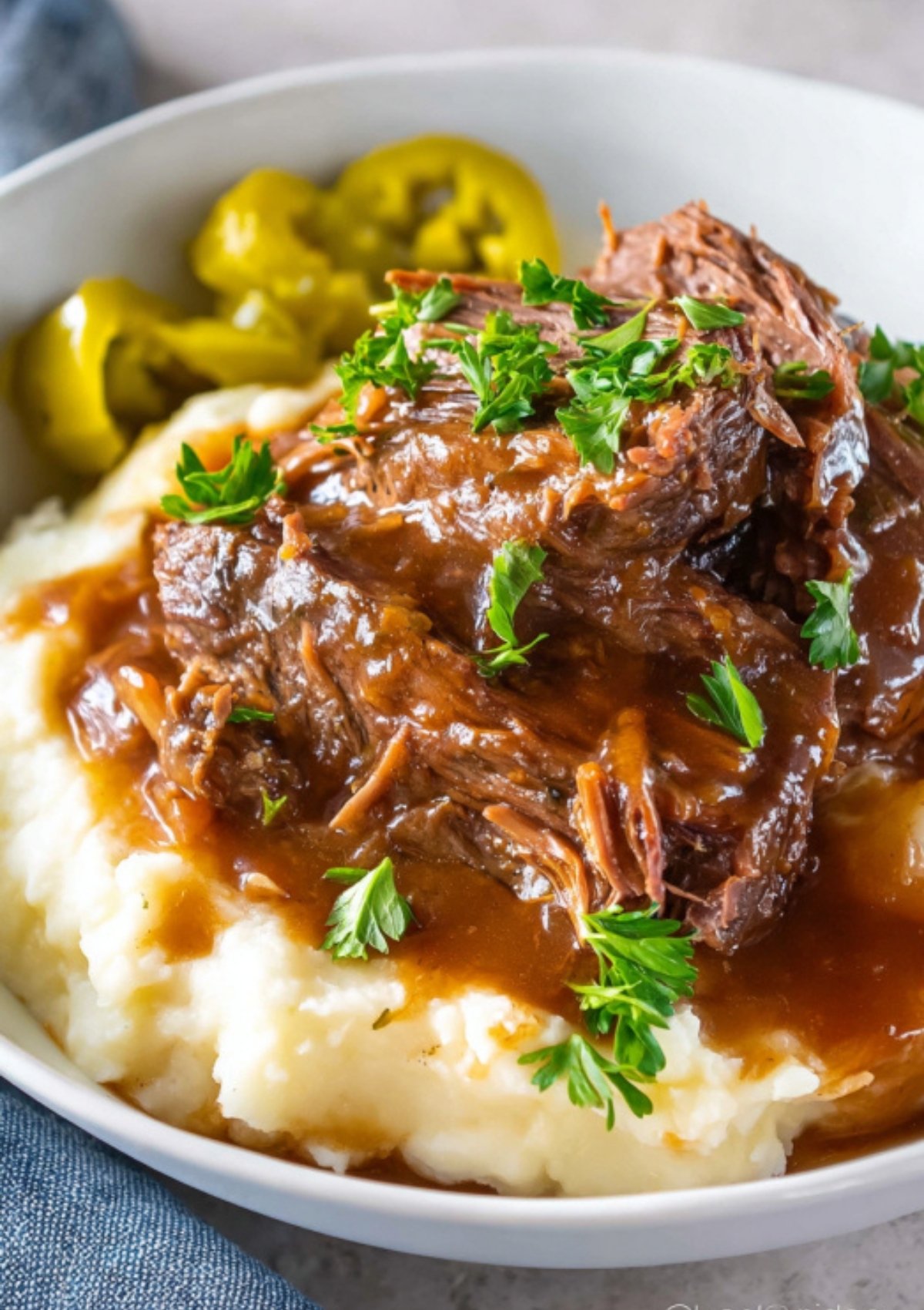 Classic Mississippi pot roast served hot over fluffy mashed potatoes with rich gravy and fresh parsley for the ultimate comfort meal.