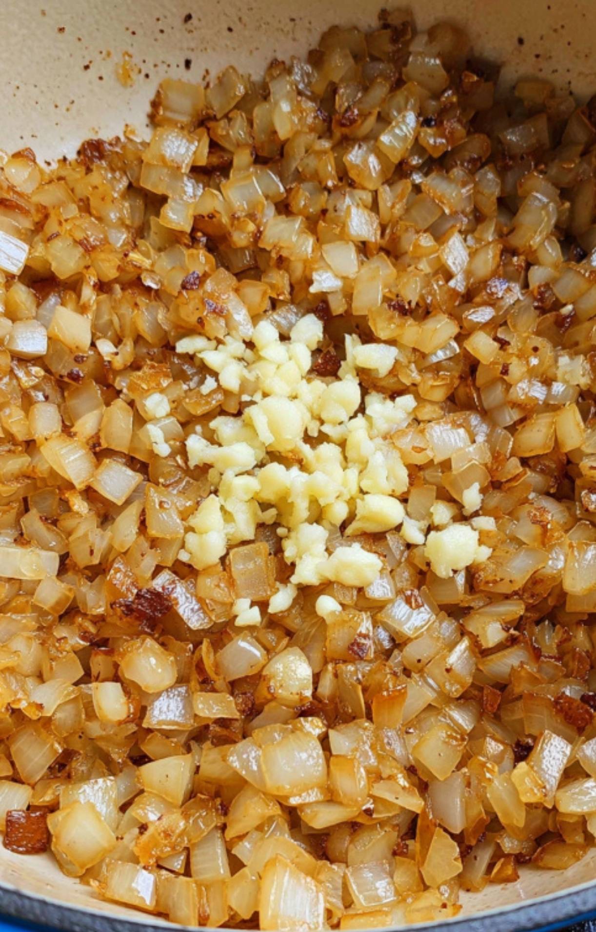 Golden onions and fresh garlic sautéing in a Dutch oven, creating a flavorful base for classic Pot Roast in the Oven.