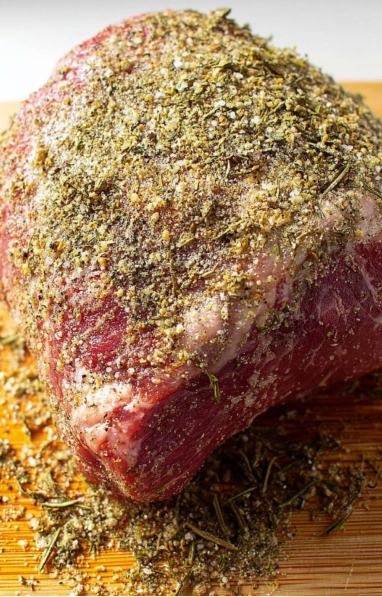Raw sirloin tip roast coated in a blend of dried herbs and seasonings, ready to cook